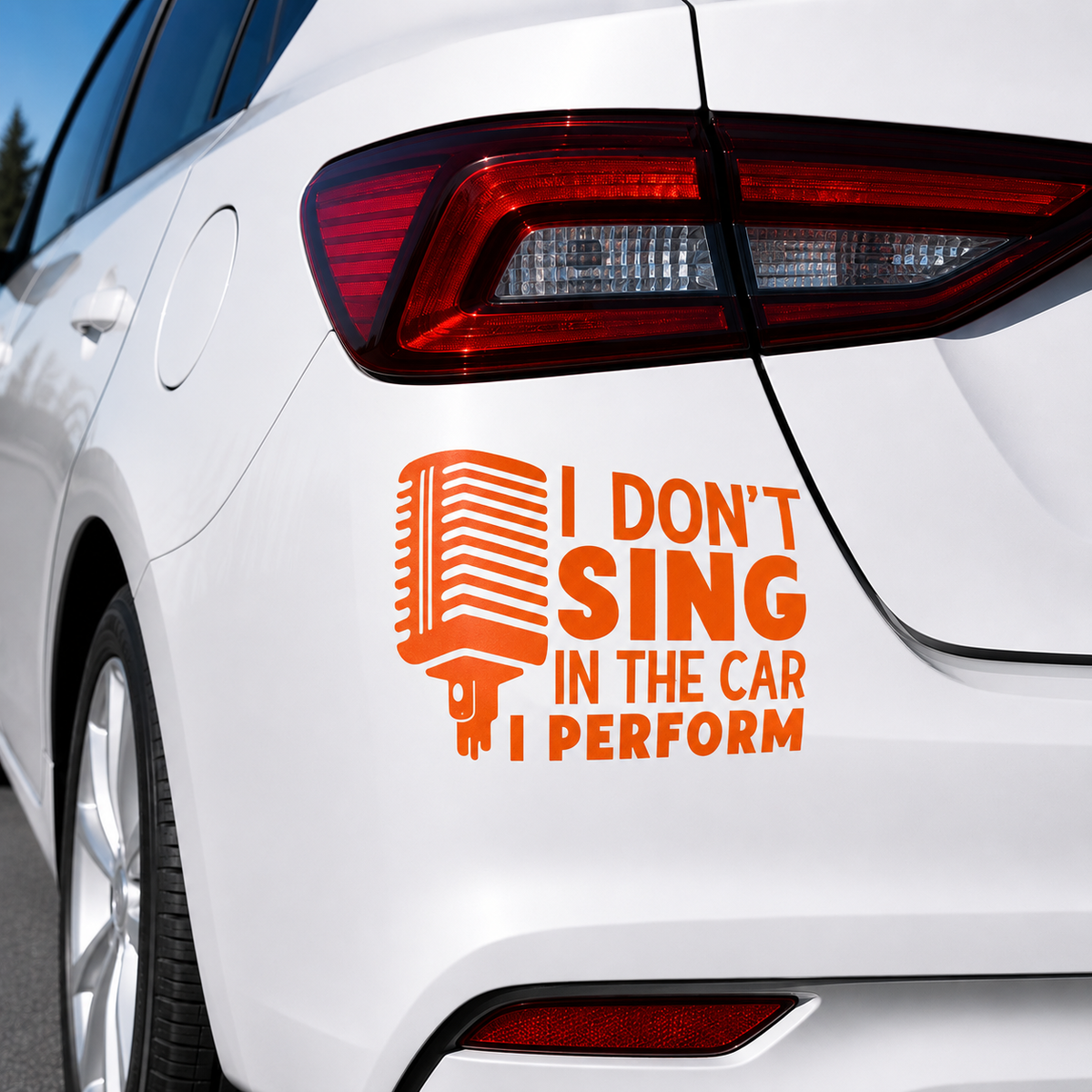 An orange vinyl car decal applied to the rear quarter panel of a white car. The decal features a retro microphone graphic and the text 'I DON'T SING IN THE CAR I PERFORM'.