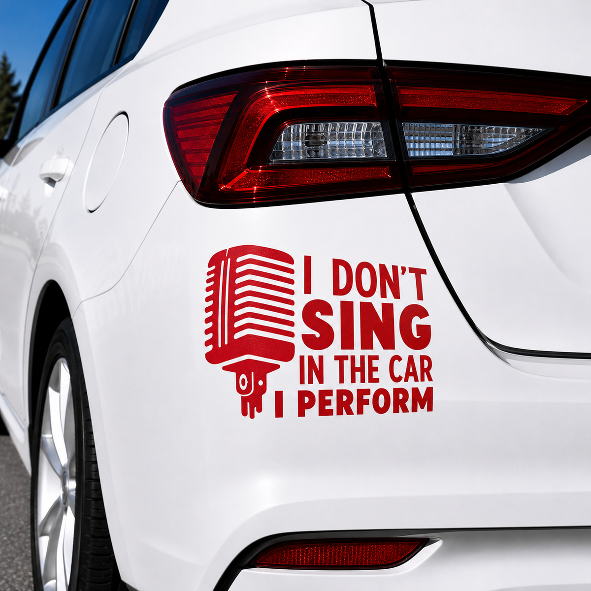 A red vinyl car decal applied to the rear quarter panel of a white car. The decal features a retro microphone graphic next to the text 'I DON'T SING IN THE CAR I PERFORM' in bold red letters.