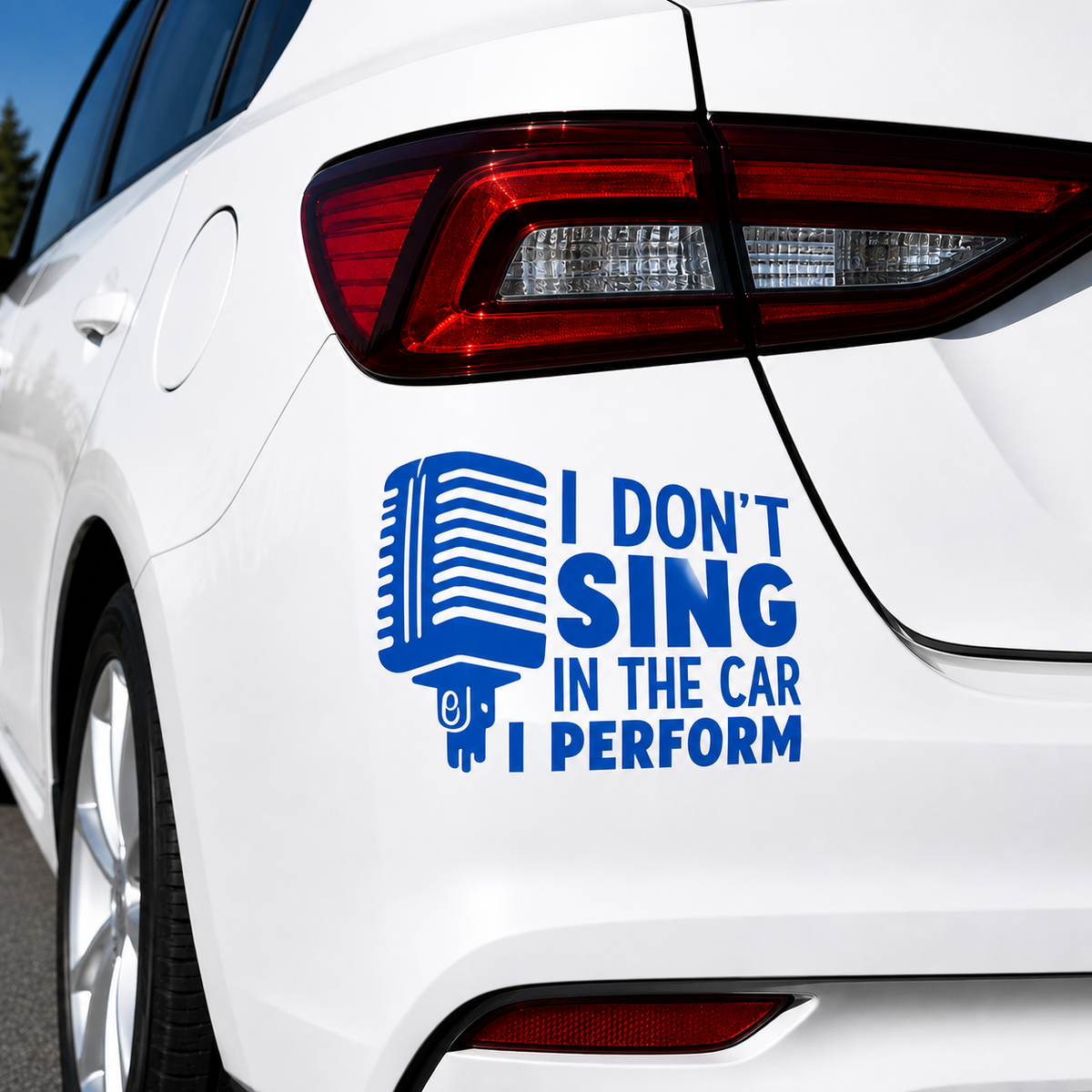 A blue vinyl car decal applied to the rear quarter panel of a white car. The decal features a retro microphone graphic and the text 'I DON'T SING IN THE CAR I PERFORM'.