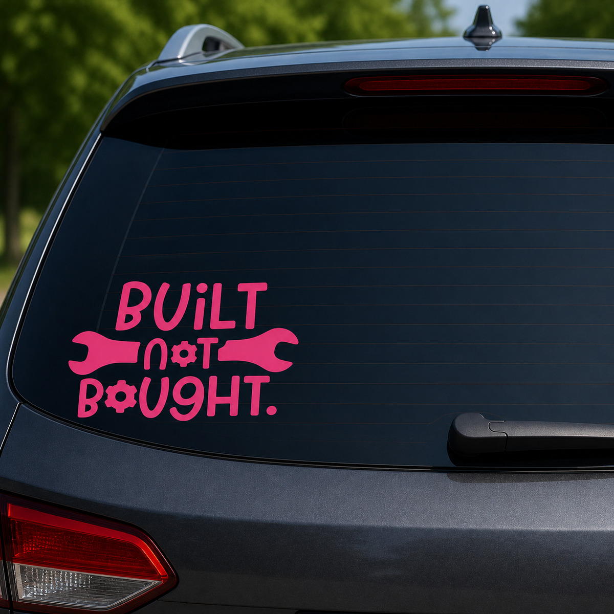 A pink vinyl decal on the rear window of a dark gray SUV. The sticker features the text 'BUILT not BOUGHT.