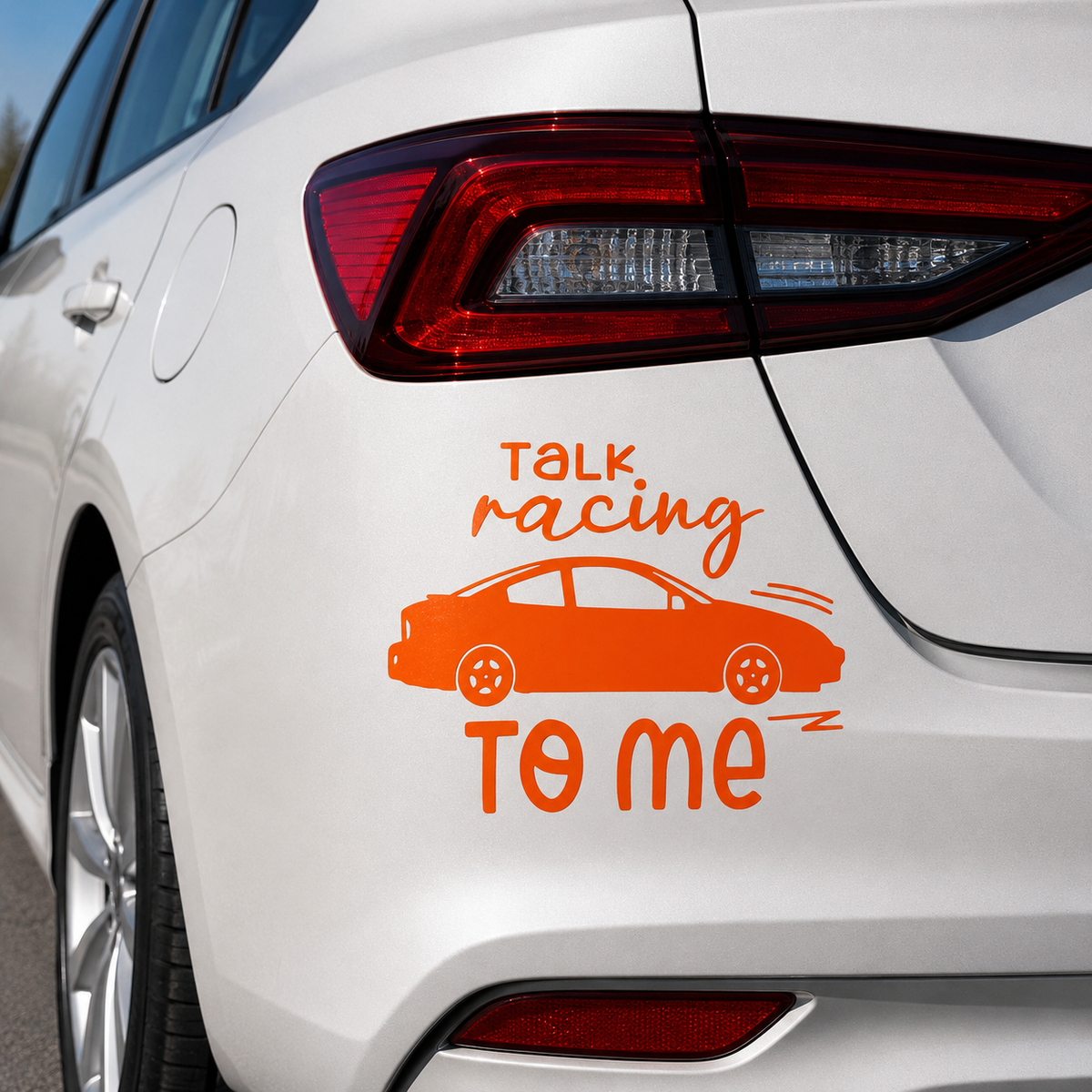 An orange vinyl car decal featuring the text 'TALK racing TO ME' with a simple car illustration, shown applied to the rear quarter panel of a white car.