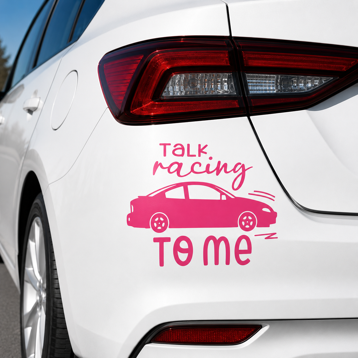 A pink vinyl car decal applied to the rear quarter panel of a white car. The decal features the text 'TALK racing TO ME' in pink lettering, with a simple side-view car silhouette in the center.
