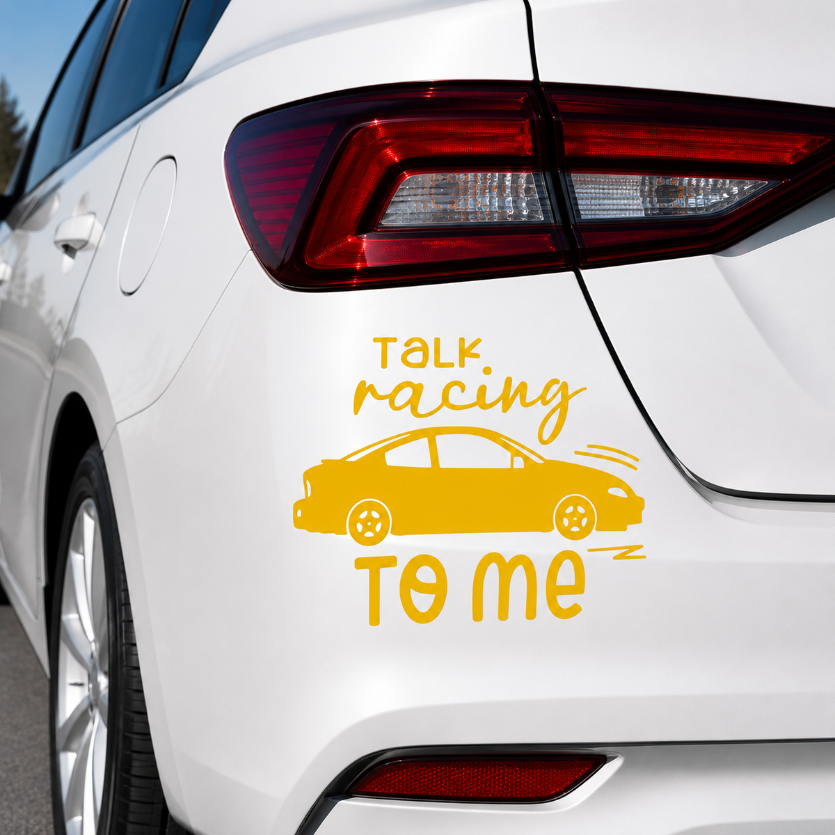 A yellow vinyl car decal applied to the rear quarter panel of a white sedan. The decal features the text 'TALK racing TO ME' in yellow script and block lettering, along with a simple side-view car illustration.