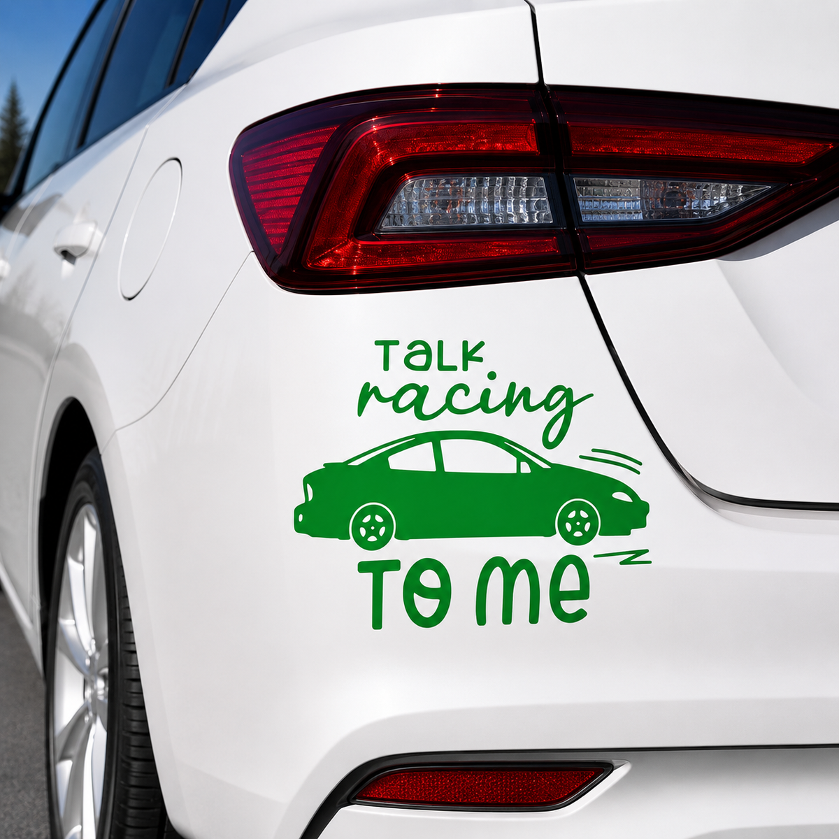 A green vinyl car decal applied to the rear quarter panel of a white sedan. The decal features the text 'TALK racing TO ME' in a stylized green font, with a simple green car silhouette in the center.