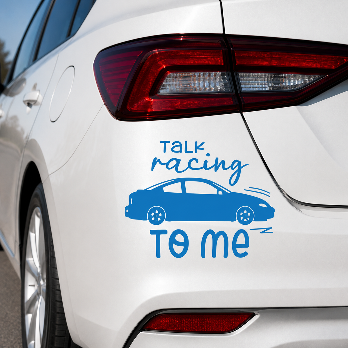 Blue vinyl car decal with the text 'talk racing TO ME' and a simple car illustration, shown applied to the rear side of a white car.