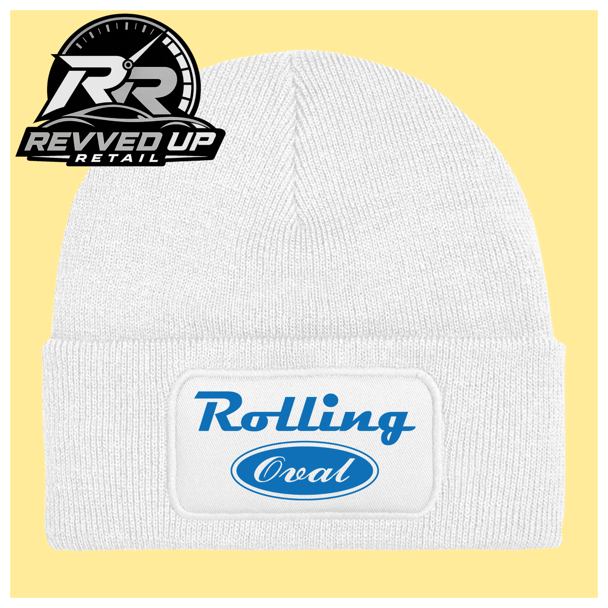A white ribbed knit beanie with a folded cuff featuring a white patch that reads 'Rolling Oval' in blue. The beanie is centered on a pale yellow background, with a Revved Up Retail logo overlay in the top-left corner.