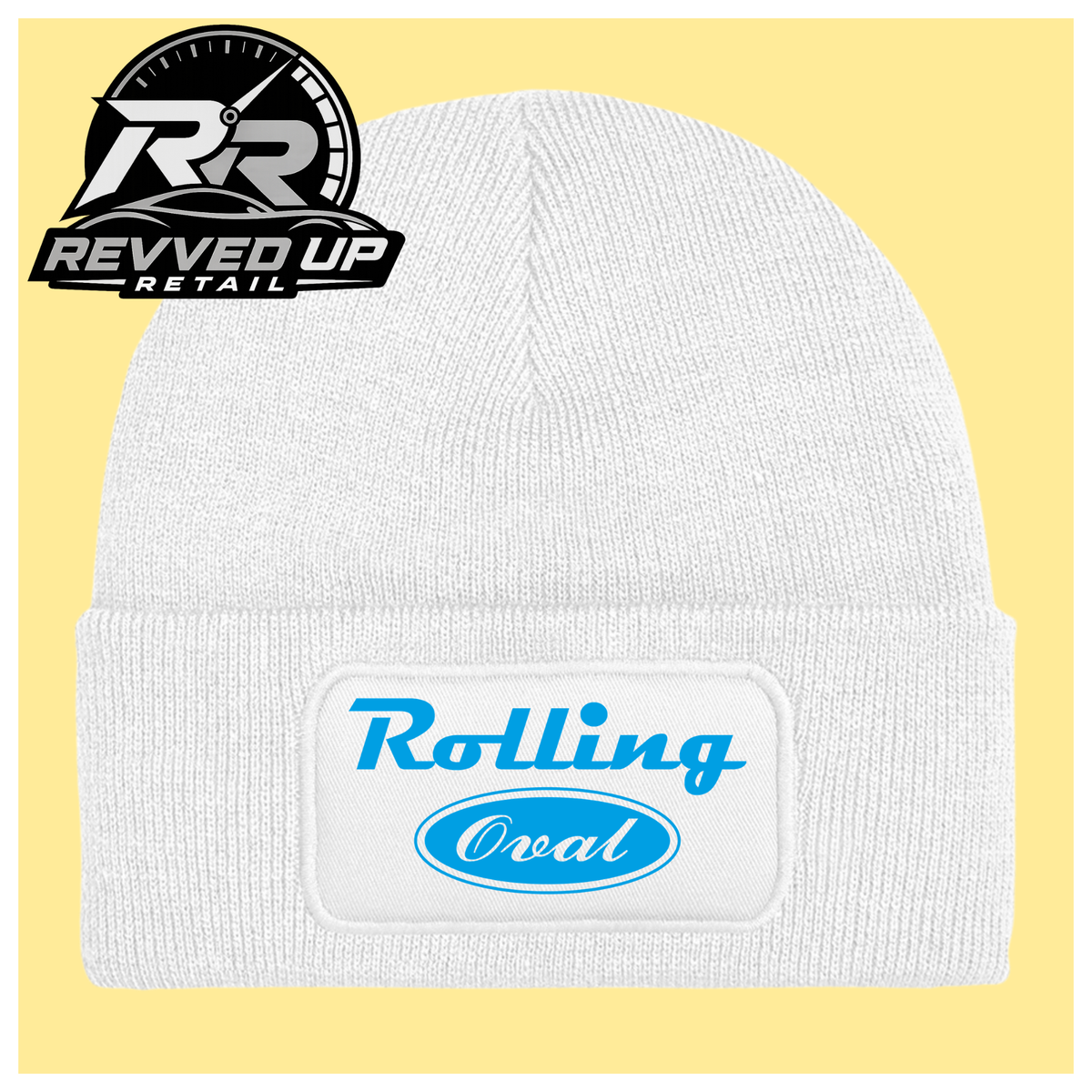 A white ribbed knit beanie hat with a folded cuff featuring a white patch that reads 'Rolling Oval' in blue. The beanie is centered on a pale yellow background, with a Revved Up Retail logo in the top-left corner.