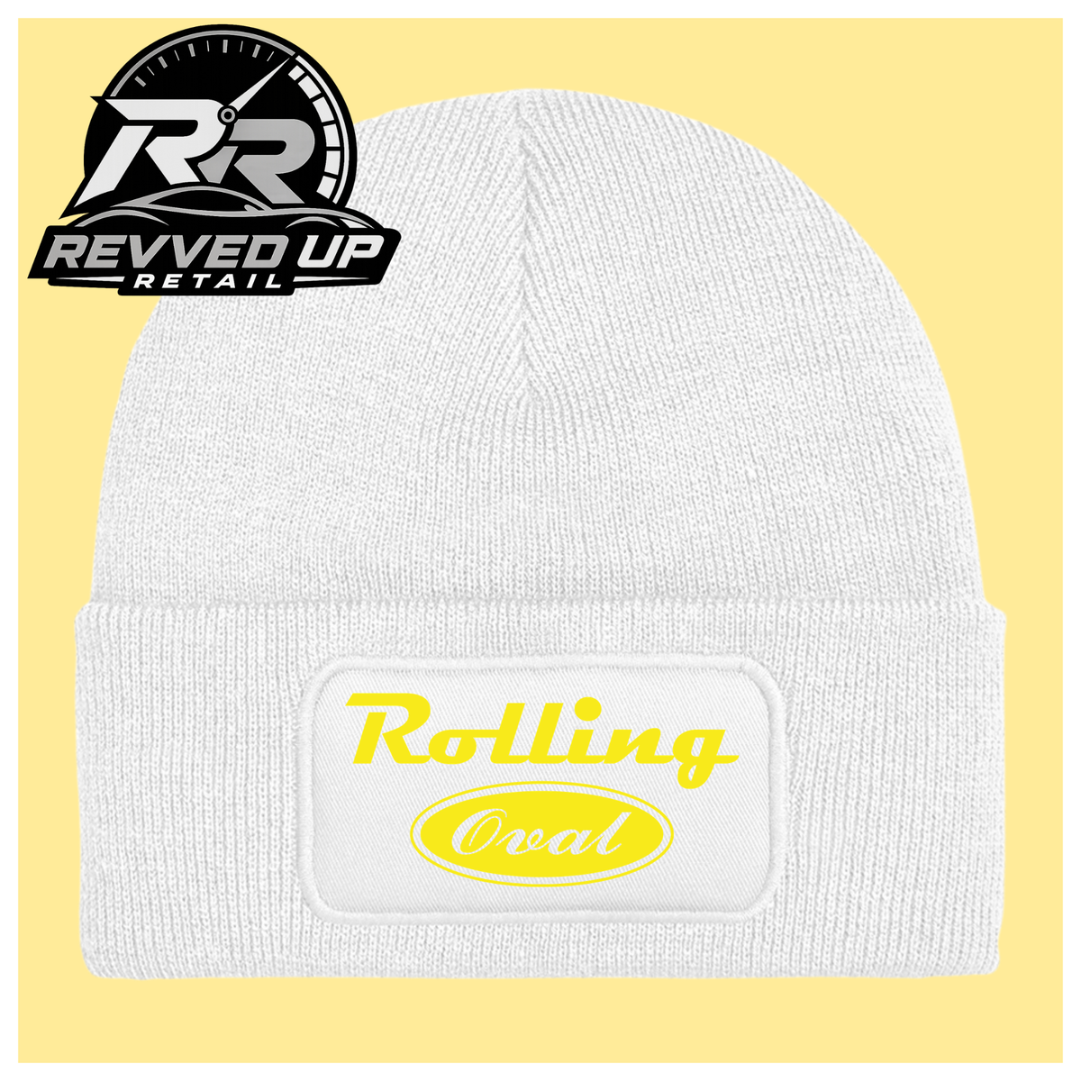 A white ribbed knit beanie with a folded cuff featuring a white patch that reads 'Rolling Oval' in yellow. The beanie is centered on a pale yellow background, with a Revved Up Retail logo overlay in the top-left corner.
