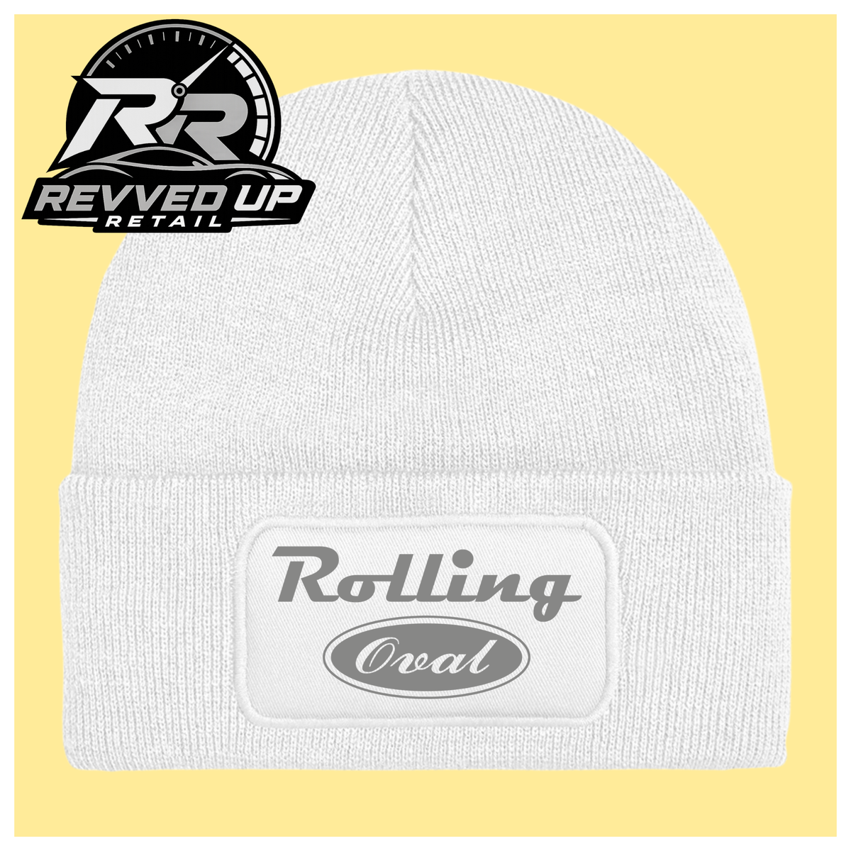 A white ribbed knit beanie with a folded cuff featuring a white patch that reads 'Rolling Oval' in grey. The beanie is centered on a pale yellow background, with a Revved Up Retail logo overlay in the top-left corner.