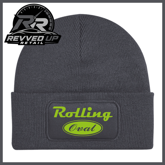 A dark grey ribbed knit beanie with a folded cuff featuring a black patch that reads 'Rolling Oval' in green. A Revved Up Retail logo is visible in the top-left corner.
