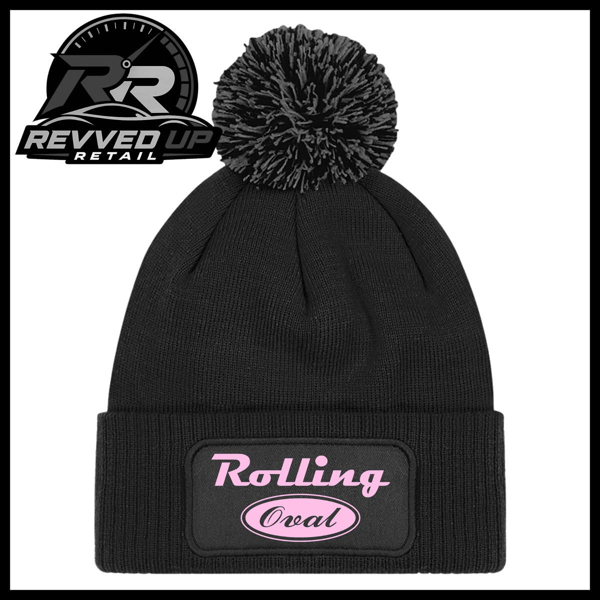 A black ribbed knit pom-pom beanie with a folded cuff featuring an oval black patch with pale pink text reading 'Rolling Oval'. A Revved Up Retail logo is visible in the top-left corner.
