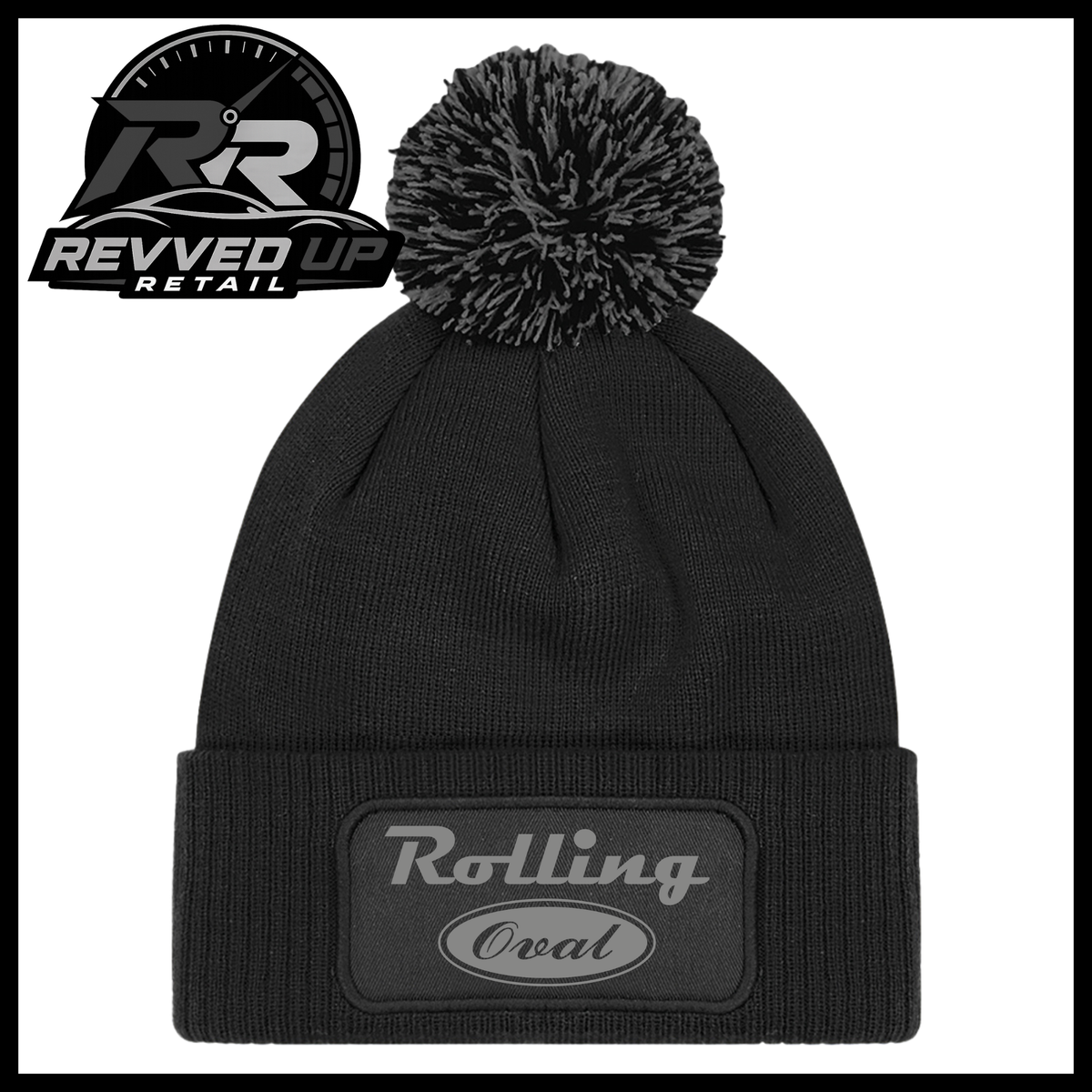 A black ribbed knit pom-pom beanie with a folded cuff featuring an oval black patch with grey text reading 'Rolling Oval'. A Revved Up Retail logo is visible in the top-left corner.