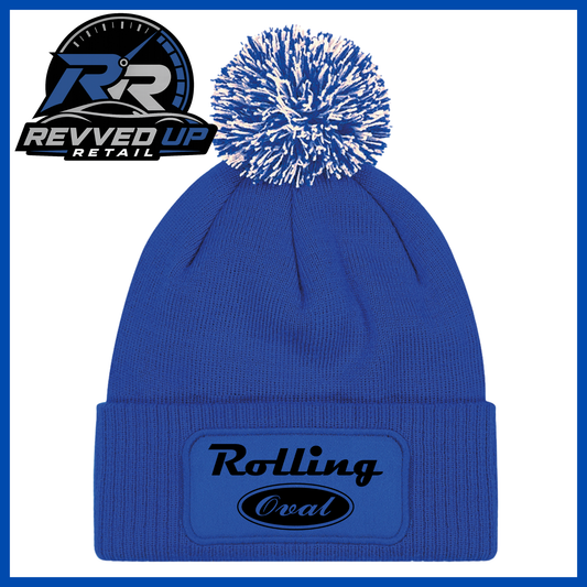 A royal blue knit beanie with a white and blue pom-pom on top and a red cuffed front patch reading 'Rolling Oval' in black. A Revved Up Retail logo appears in the upper left corner.