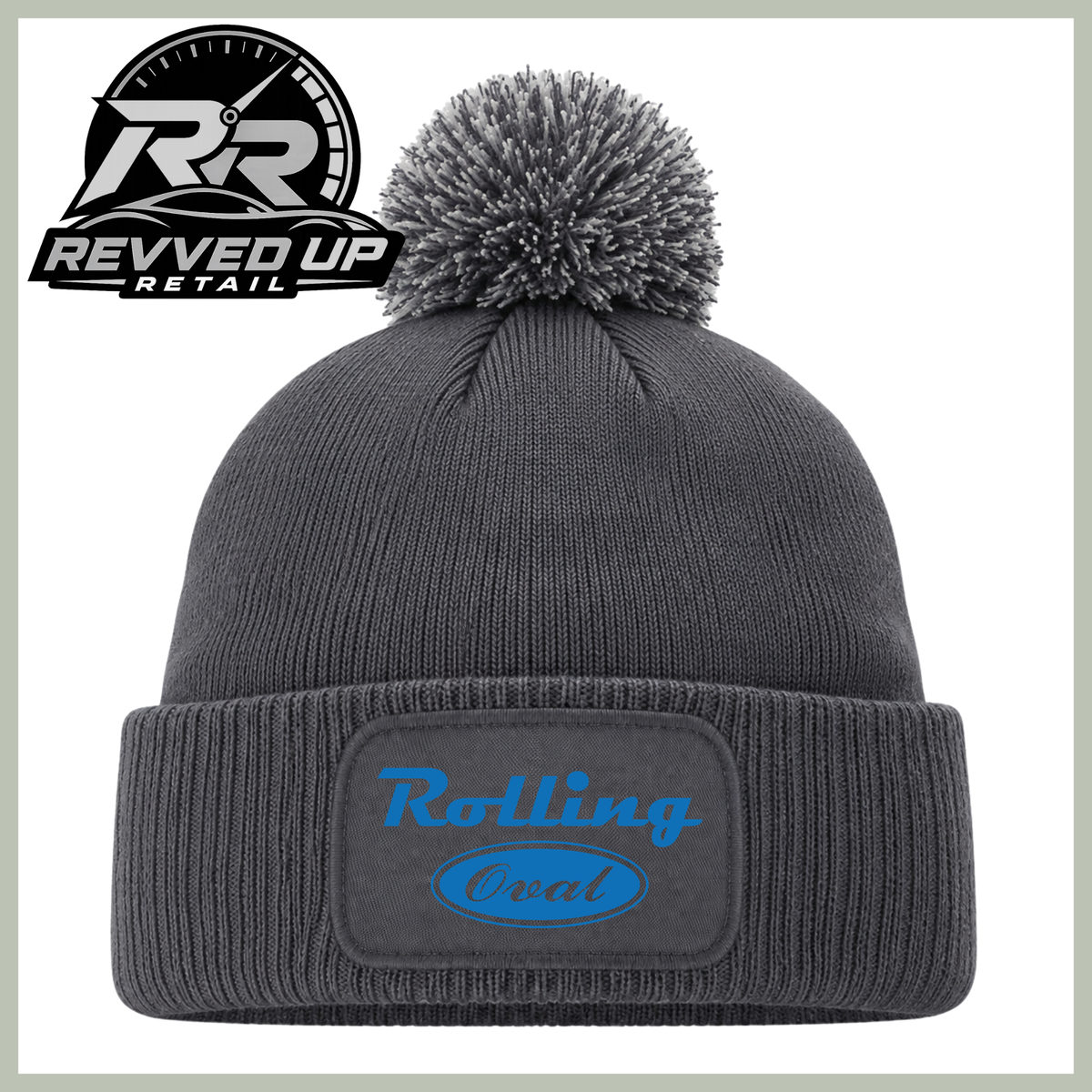 A dark gray ribbed knit beanie with a matching pom-pom and a folded cuff featuring a patch with the words 'Rolling Oval' in blue. A Revved Up Retail logo is visible in the top left corner.