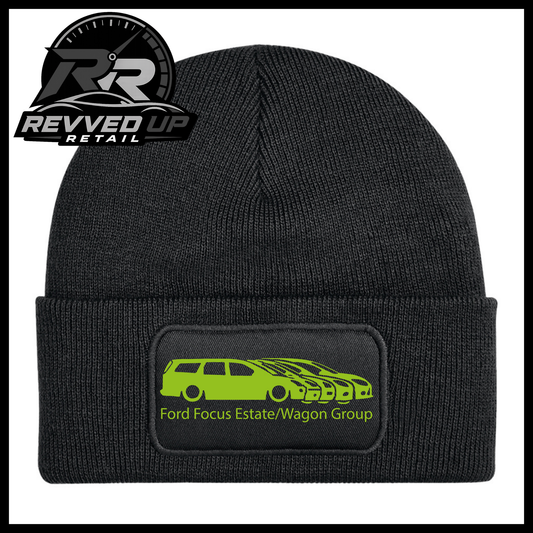 A black ribbed knit beanie with a folded cuff, featuring a black rectangular patch with a green car graphic and the text 'Ford Focus Estate/Wagon Group.' A Revved Up Retail logo appears in the top-left corner.