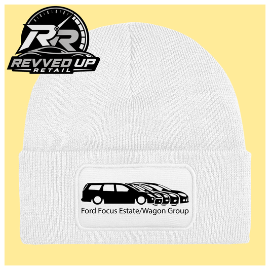 A white ribbed knit beanie with a folded cuff, featuring a black rectangular patch with a black car graphic and the text 'Ford Focus Estate/Wagon Group.' A Revved Up Retail logo appears in the top-left corner.