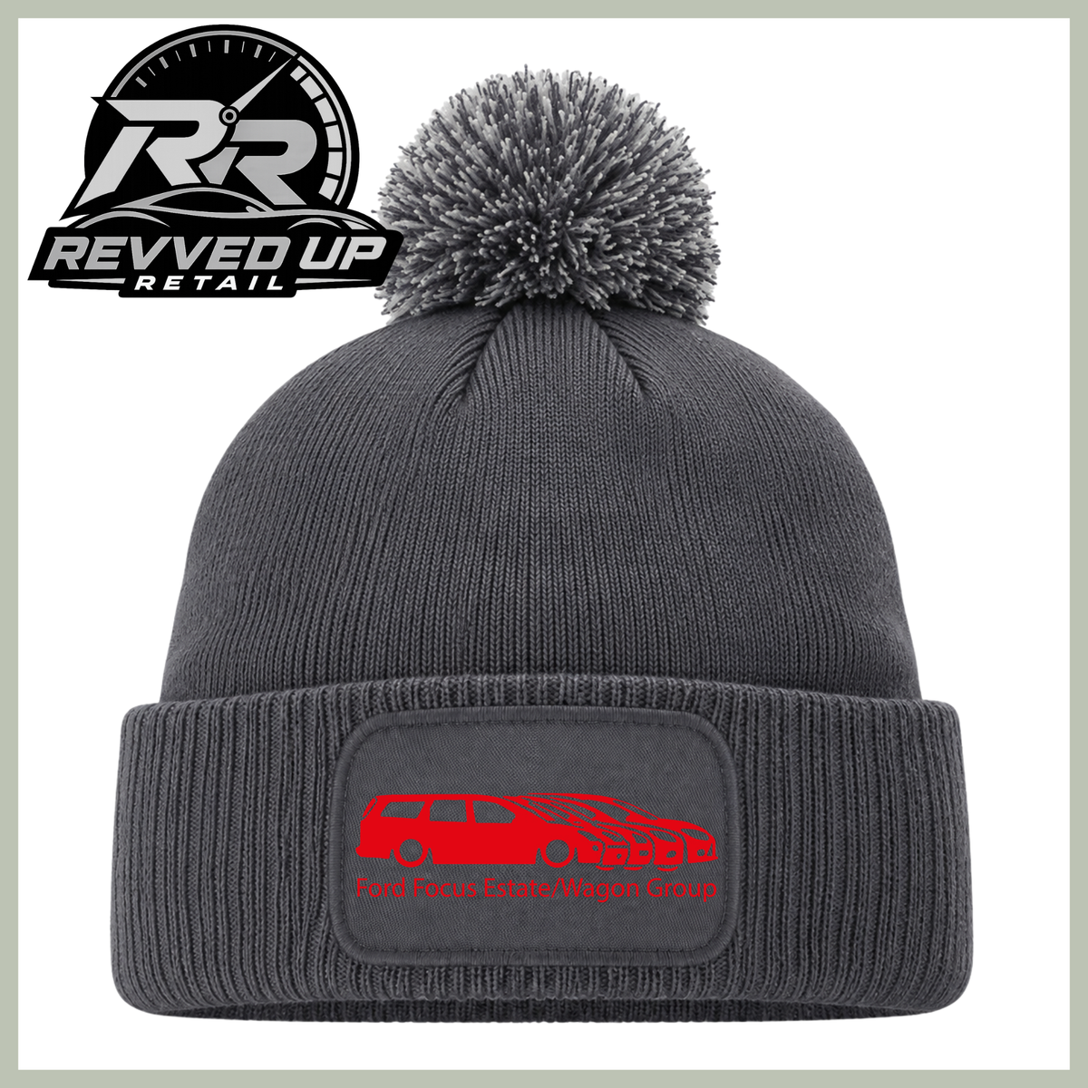 A dark gray ribbed knit beanie with a matching gray pom-pom on top and a folded cuff featuring a rectangular patch with a red car graphic and the text 'Ford Focus Estate/Wagon Group'. The Revved Up Retail logo is displayed in the upper left corner.