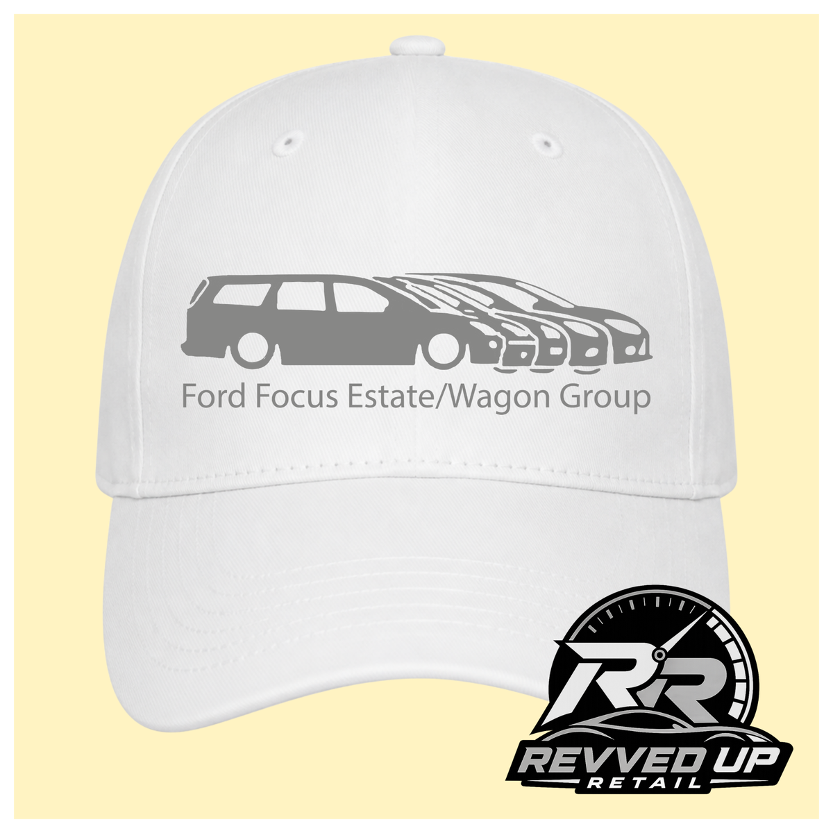 A white baseball cap with a gray graphic of Ford Focus estate and wagon cars and the text 'Ford Focus Estate/Wagon Group' on the front, shown against a pale yellow background. A Revved Up Retail logo is visible in the bottom right corner.