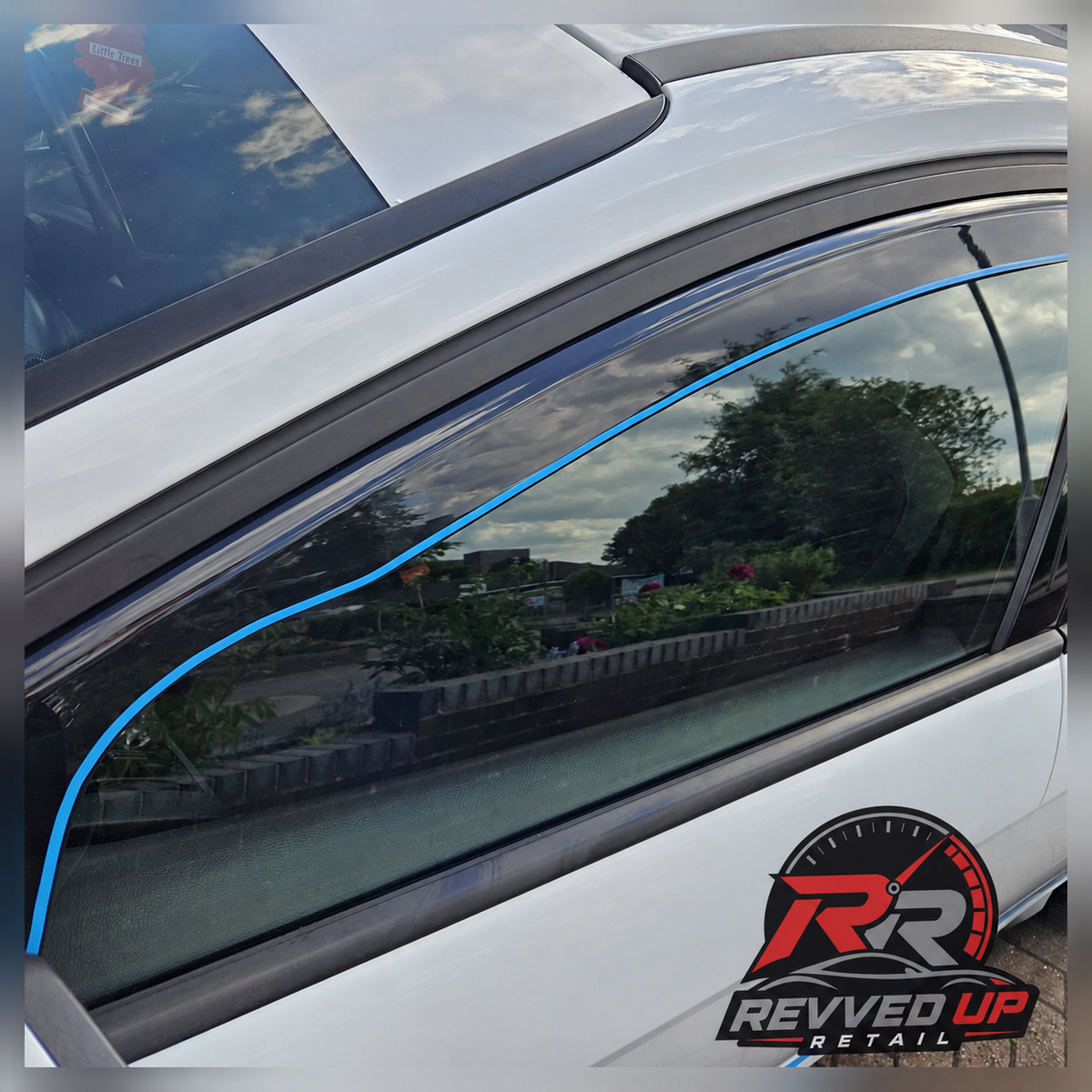 A close-up of a white car door with a black rubber weatherstrip around the side window, highlighted by a blue line overlay. A Revved Up Retail logo is visible in the bottom right corner.