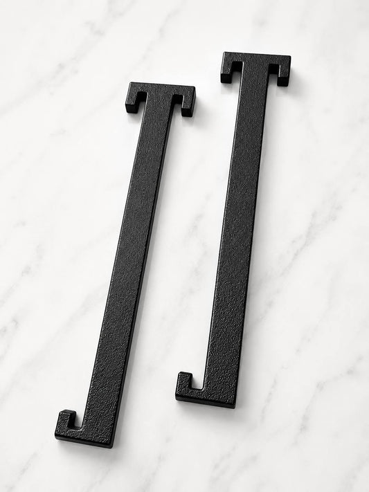Two black plastic cast letter L-shaped cabinet pulls displayed on a white marble surface.