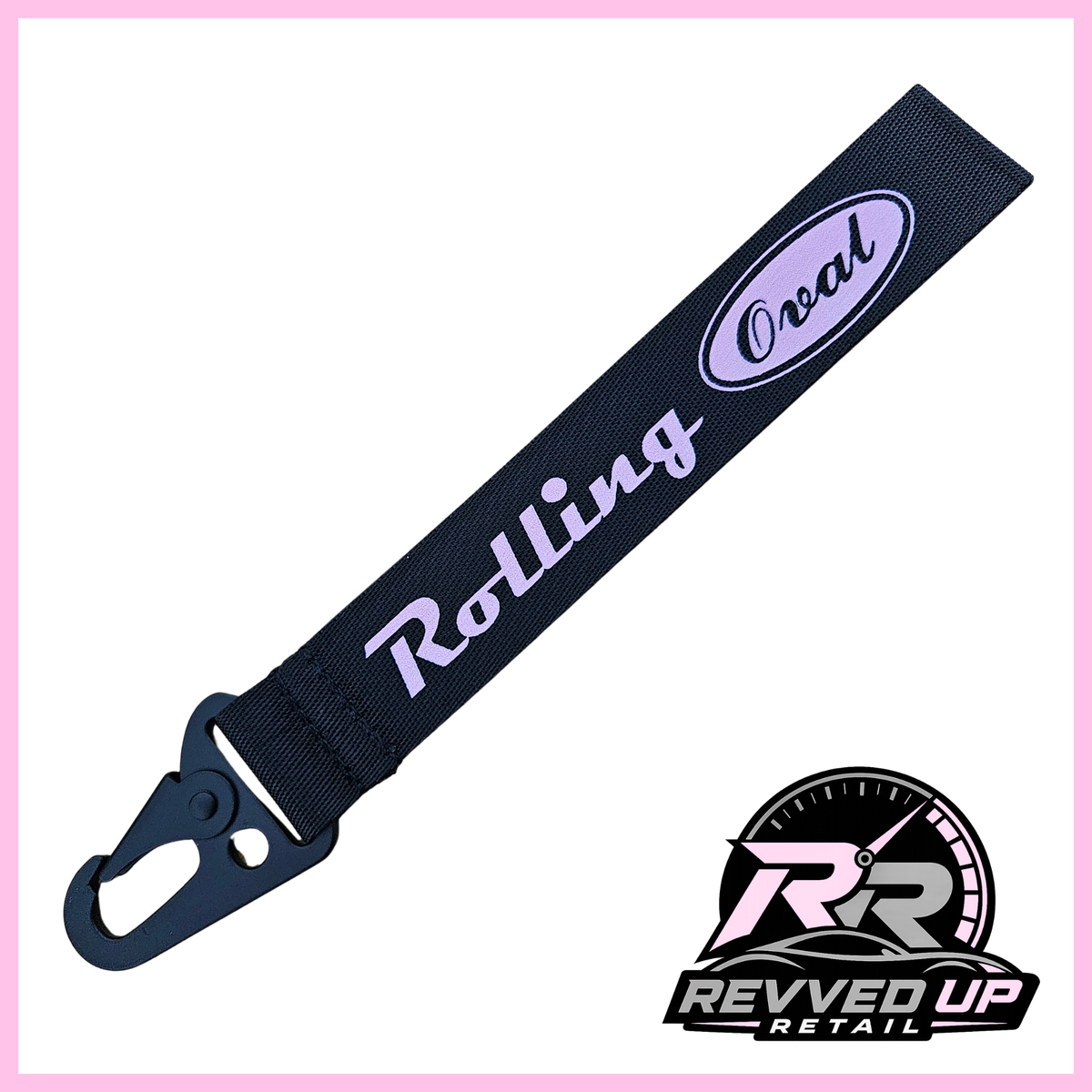 A Rolling Oval brand wristlet strap in black with pale pink printed logos and a black metal carabiner clip, shown on a white background with a Revved Up Retail watermark.