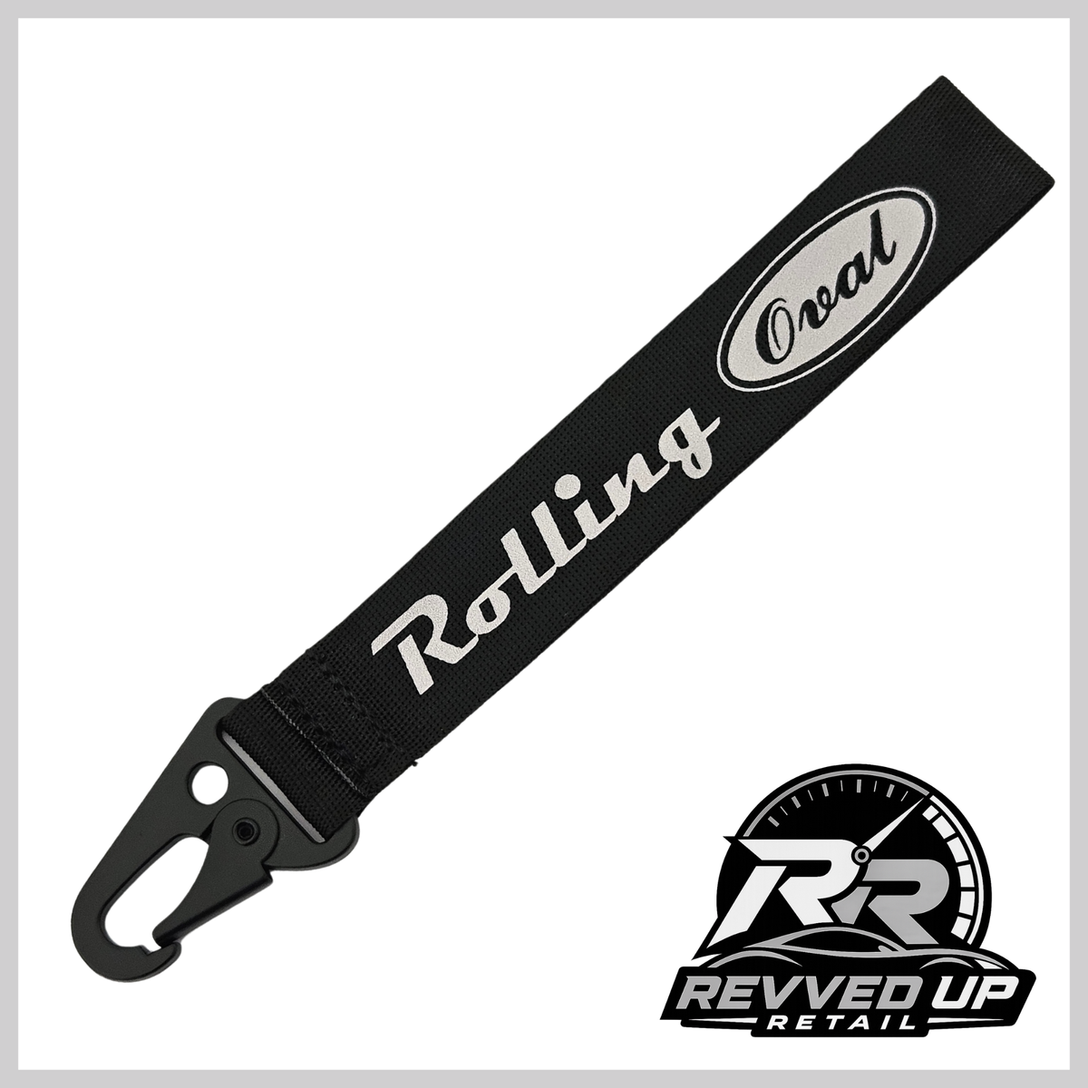 A Rolling Oval brand wristlet strap in black with grey printed logos and a black metal carabiner clip, shown on a white background with a Revved Up Retail watermark.