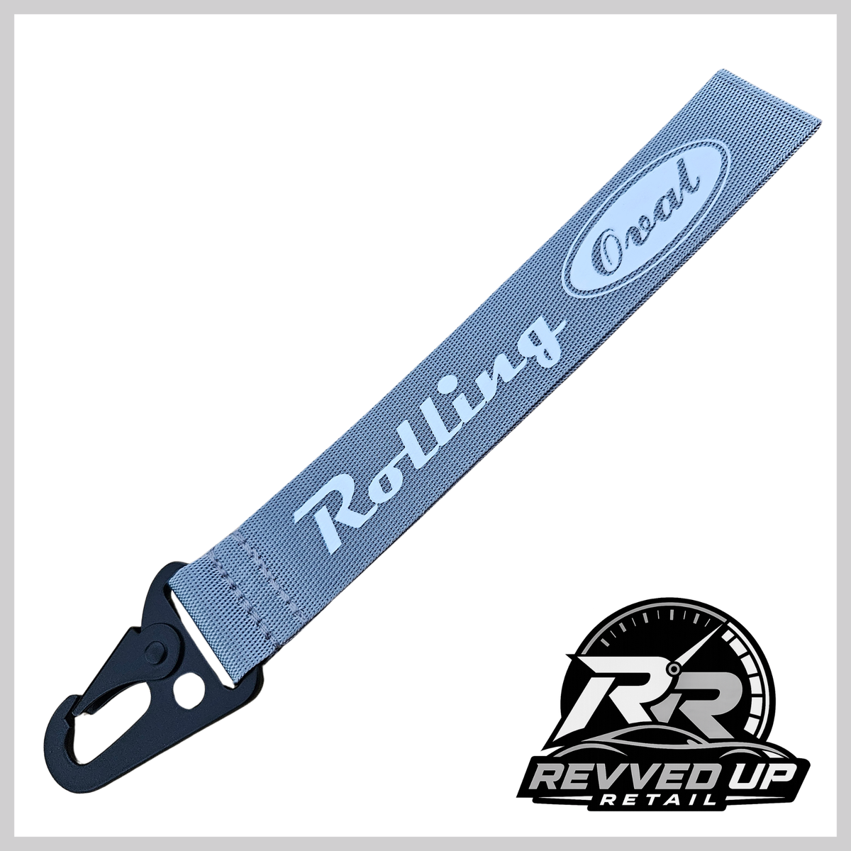 A Rolling Oval brand wristlet strap in grey with white printed logos and a black metal carabiner clip, shown on a white background with a Revved Up Retail watermark.