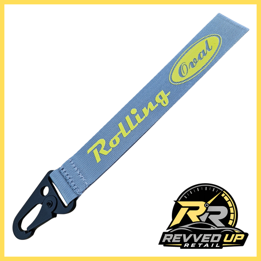 A Rolling Oval brand wristlet strap in grey with yellow printed logos and a black metal carabiner clip, shown on a white background with a Revved Up Retail watermark.