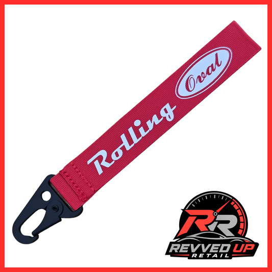 A Rolling Oval brand wristlet strap in red with white printed logos and a black metal carabiner clip, shown on a white background with a Revved Up Retail watermark.
