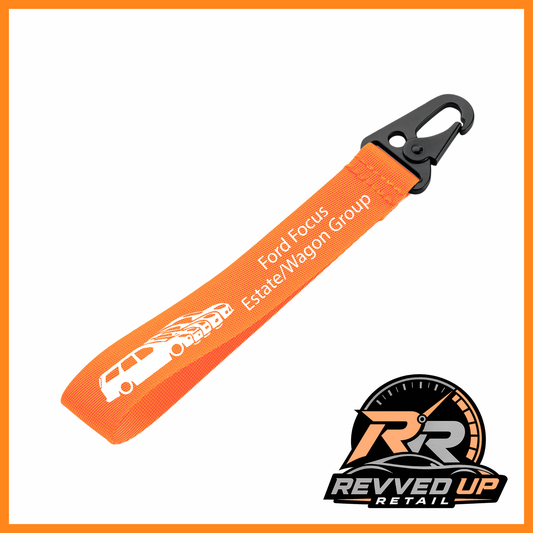 A Ford Focus Estate/Wagon Group brand wristlet strap in orange with white printed logos and a black metal carabiner clip, shown on a white background with a Revved Up Retail watermark.